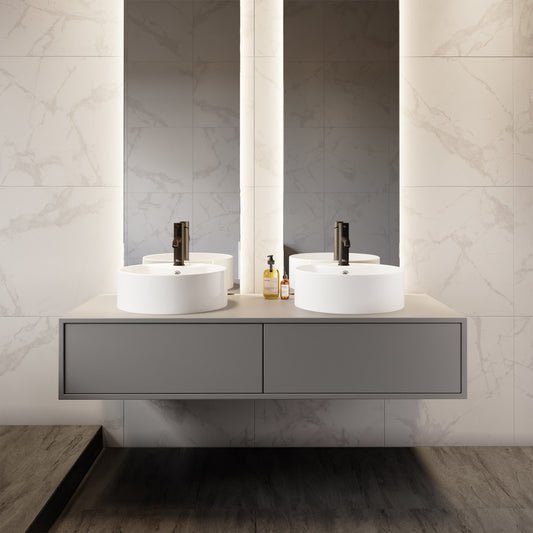 Round white vessel sink with faucet mount on a floating gray vanity against marble wall.