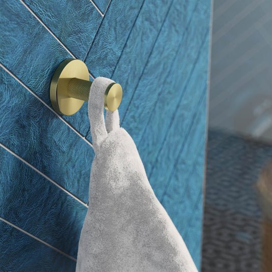 Brushed gold stainless steel bathroom robe hook mounted on blue textured wall holding white towel.