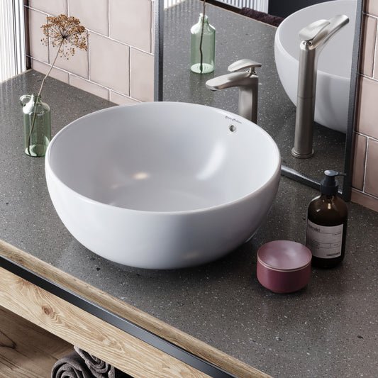 Round white ceramic vessel sink on dark countertop with brushed metal faucet.
