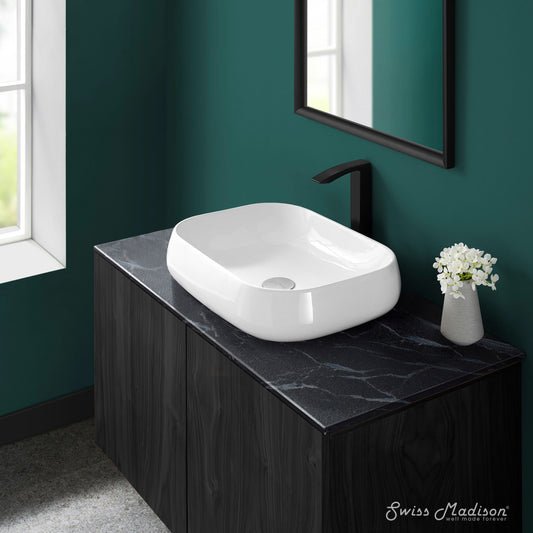 Square white ceramic vessel sink with rounded edges on black marble countertop.