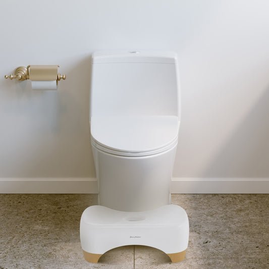 Aqua 7" toilet stool in oak wood with curved design placed in front of modern white toilet.