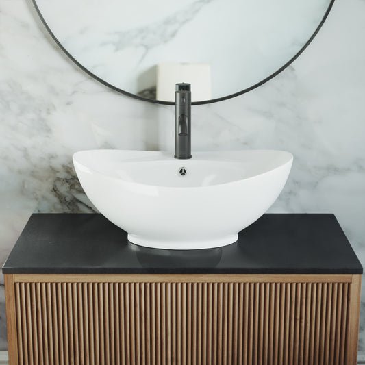 Oval white ceramic vessel sink with single drain hole on black countertop.