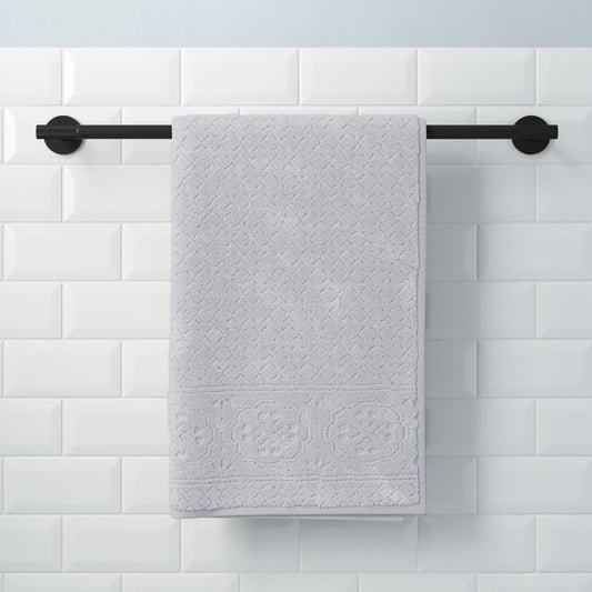 24-inch matte black towel bar with round wall mounts and gray towel against white subway tile wall.