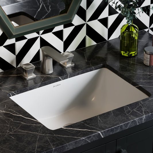 Rectangular under-mount bathroom sink in white with polished chrome single-handle faucet on black marble countertop.